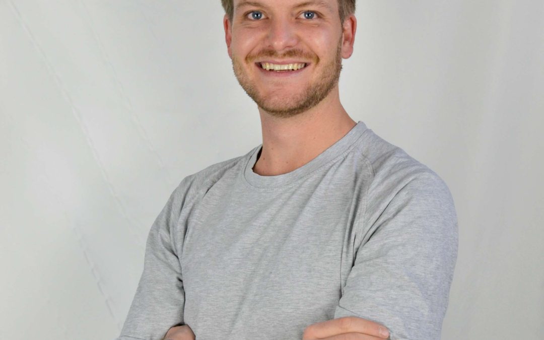 Das Passbild zeigt Josua Wieser mit einem hellen Hintergrund. Er trägt ein helles Shirt und lächelt in die Kamera.