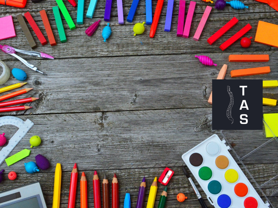 Gesunde Schule? Das Bild zeigt aus der Vogelperspektive einen dunklen Holztisch, in einem Kreis liegen unterschiedliche Kreidefarben und Buntstifte.